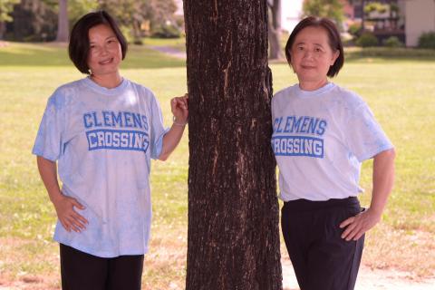 Photo of 2 Cafeteria staff posing under a tree.